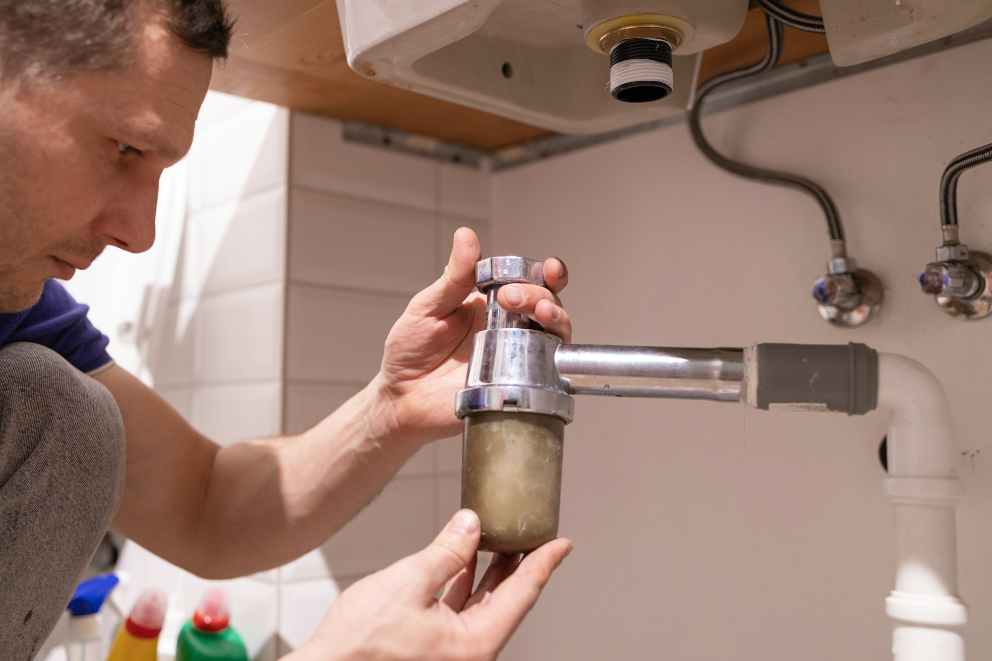 Caucasian male plumber fixing a sink in the bathroom